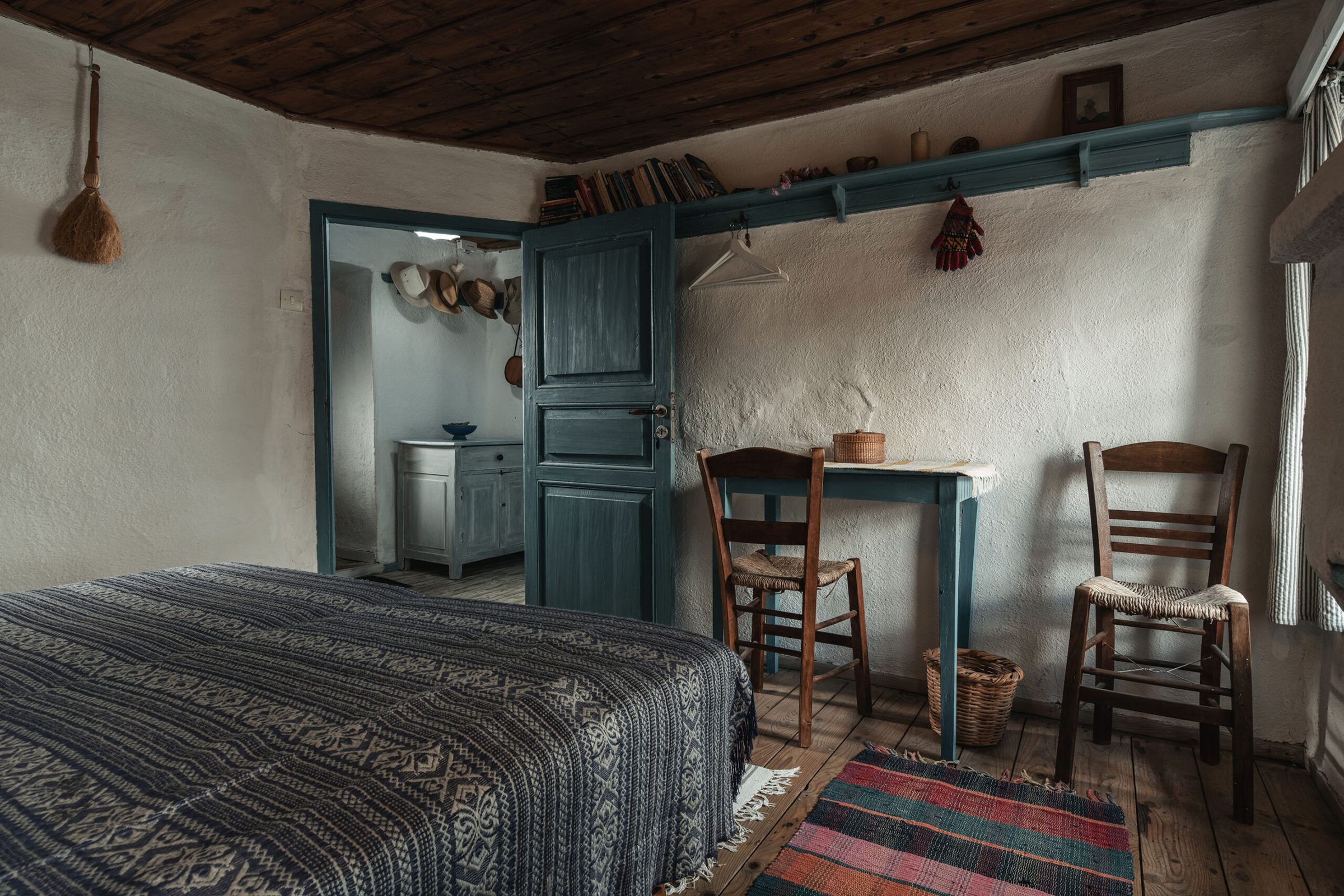 A whitewashed room with painted woodwork, rush chairs and a woven rug